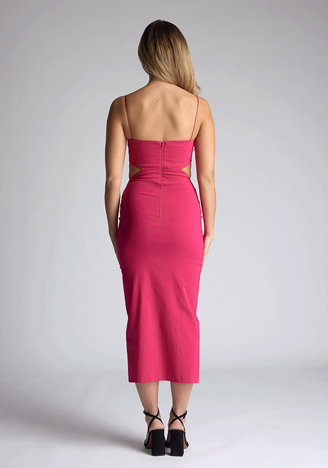 Back image of a model wearing a magenta midaxi dress with a graceful scoop neckline, slender straps, subtle side cut-out and it offers both mobility and modern flair with a front skirt split. The design featured is the Vesper Marilynn Magenta Midaxi Dress