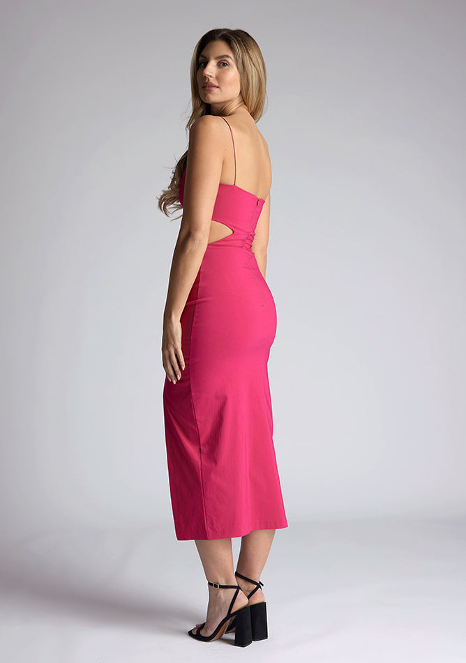 Back quarter image of a model wearing a magenta midaxi dress with a graceful scoop neckline, slender straps, subtle side cut-out and it offers both mobility and modern flair with a front skirt split. The design featured is the Vesper Marilynn Magenta Midaxi Dress