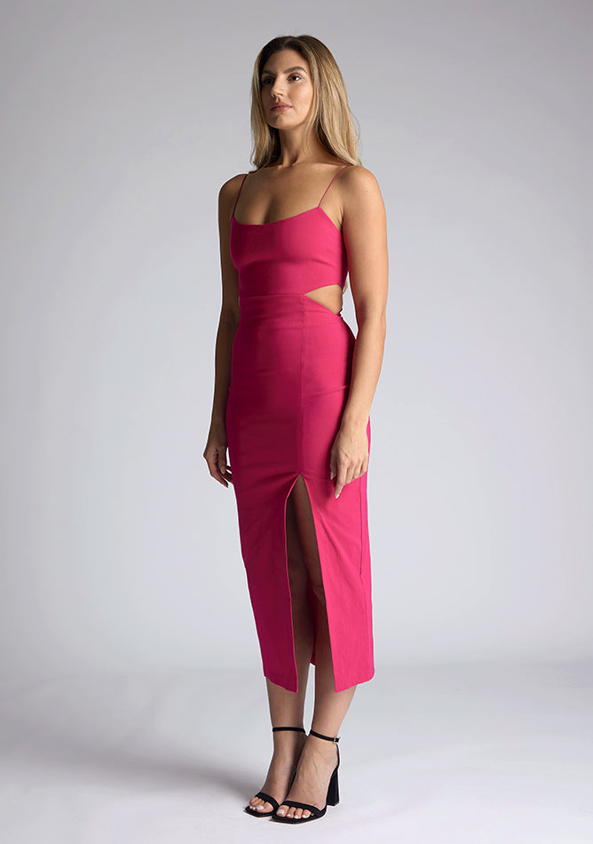 Front quarter image of a model wearing a magenta midaxi dress with a graceful scoop neckline, slender straps, subtle side cut-out and it offers both mobility and modern flair with a front skirt split. The design featured is the Vesper Marilynn Magenta Midaxi Dress